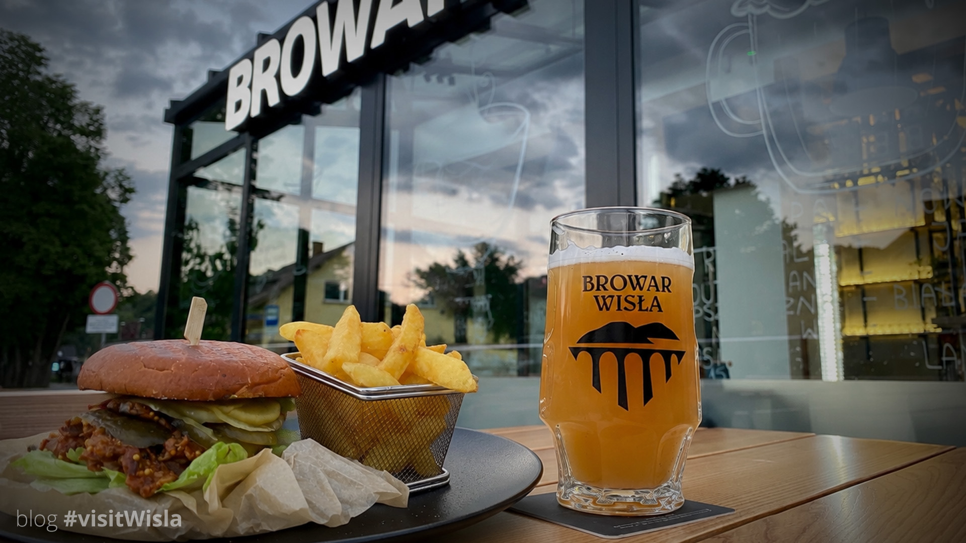 Burger z frytkami i szklanka piwa przed Browarem Wisła