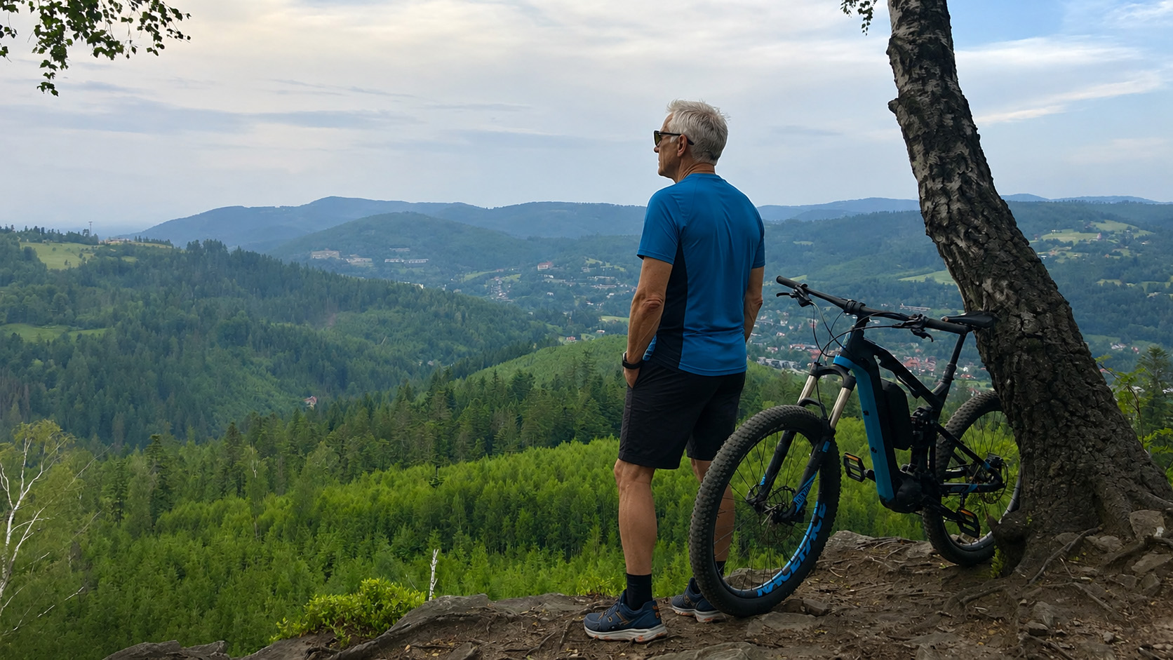 Rowerzysta z rowerem elektrycznym podziwiający panoramę Beskidów